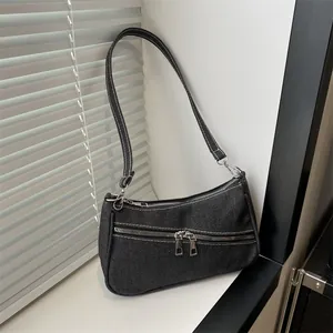 Detail of dark grey denim underarm bag featuring white contrast stitching and silver zippers
