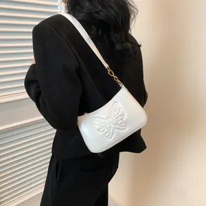 Close-up of white glossy leather shoulder bag with embossed butterfly and gold buckle