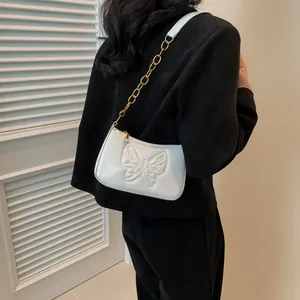 Detailed view of the white glossy leather bag featuring 3D butterfly embossed patterns
