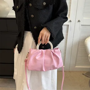 Gros plan du sac nuage rose avec poignée en perles et texture en cuir plissé élégant