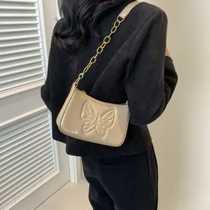 Close-up of a glossy beige patent leather bag featuring a detailed butterfly embossed pattern
