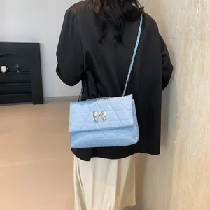 Quilted light blue chain crossbody bag with silver bow accent on model