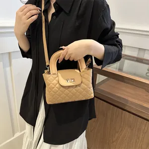 Detail view of beige quilted leather crossbody bag featuring a gold twist-lock closure