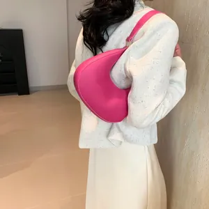 Close-up of rose pink crescent shoulder bag with smooth texture and golden hardware