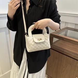 Close-up of cream quilted handbag featuring gold twist lock and elegant top handle