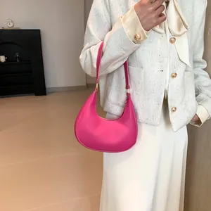 Detail view of a rose pink crescent shoulder bag in premium faux leather with gold accents