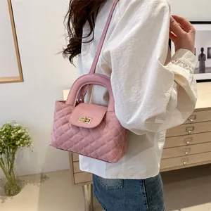 Pink quilted leather handbag with gold twist lock shown in a cozy home interior setting