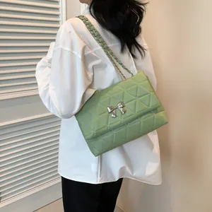Quilted light green crossbody bag with silver bow detail worn by model with white shirt