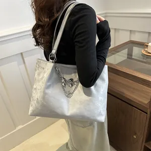 Silver metallic velvet tote bag with chain strap and bow charm on female model