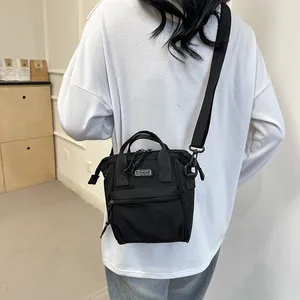 Rear view of a minimalist black canvas crossbody bag with sport fashion logo and strap