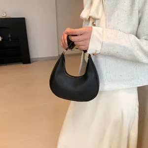 Detail of elegant black hobo bag paired with a cream tweed jacket and silk dress