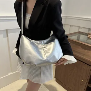 Silver metallic crescent crossbody bag with minimalist shoulder strap and chic branding