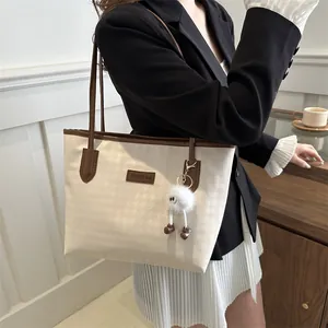 Side view of houndstooth tote bag with brown leather trim and plush doll charm