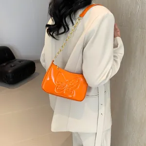 Orange patent leather shoulder bag with butterfly relief and gold chain strap