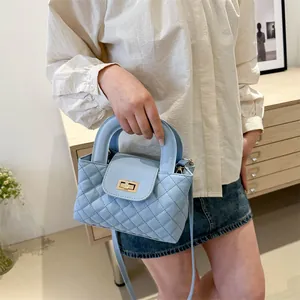 Close-up of light blue quilted crossbody bag with golden twist lock and chain strap
