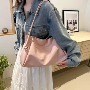 Close-up of pink tote bag featuring embossed letters and knotted shoulder strap detail