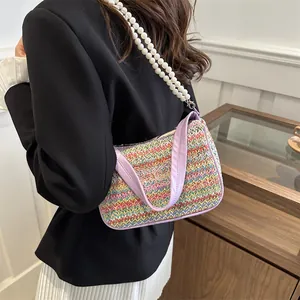 Detailed view of a woven colorful beach bag featuring purple butterfly embroidery and pearls