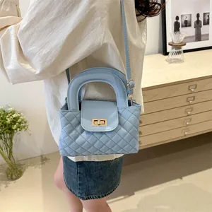 Detailed view of light blue quilted handbag with gold lock and rigid top handle
