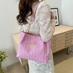 Dettaglio della borsa tote rosa a pieghe con catena dorata sulla spalla della modella