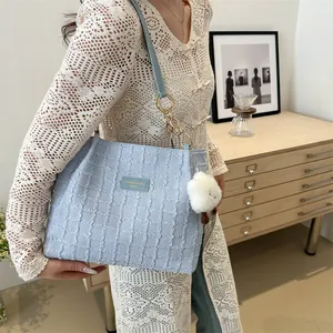 Dettaglio della borsa tote trapuntata celeste con catena dorata e ciondolo a agnello