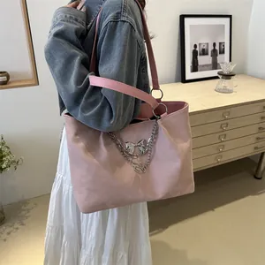 Detail of pink tote bag showing silver chain, initial logo, and bow decoration
