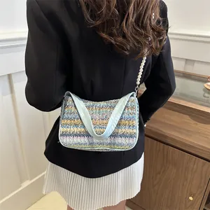Close-up of woven straw bag featuring butterfly embroidery and pearl chain handle