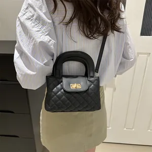 Detail of black quilted chain bag with gold rotary lock shown on model's shoulder