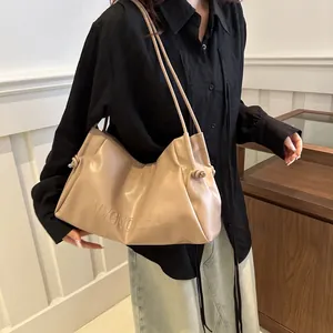 Detail of minimalist beige tote bag featuring VVGN ZHU embossed lettering and side knots