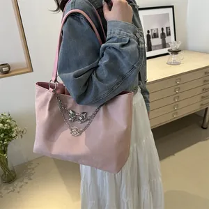 Pink tote bag detail with silver chain, bow pendant and stylish crossbody strap design