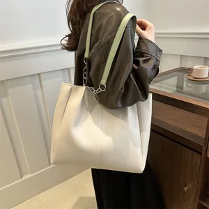 Close-up detail of pleated cream tote bag with green leather and silver chain strap