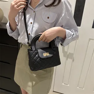 Close-up of quilted black handbag with golden square twist lock and stylish chain strap