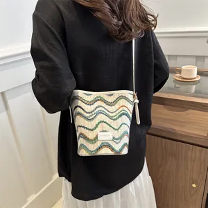 Detail of colorful woven shoulder bucket bag with wavy pattern and fashion logo