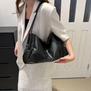 Close-up of black leather tote bag with embossed WANOGZHU letters and knot shoulder strap