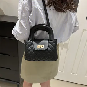 Detailed view of black quilted chain bag with gold twist-lock and circular handle
