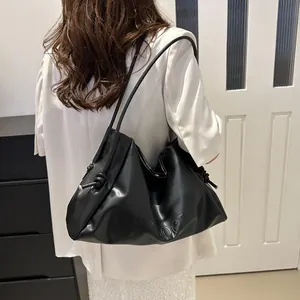 Detail of VVOGTH letter embossing and side knot on black leather tote bag