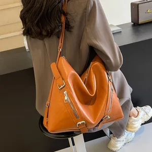 Close-up of vintage brown leather tote bag with silver zippers and adjustable strap