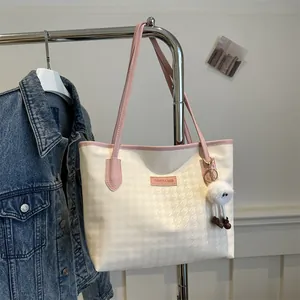 Detail of cream tote bag with pink trim, houndstooth texture and plush charm on stand