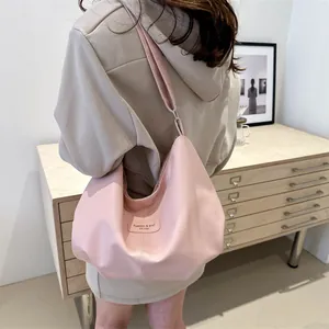 Detail of light pink shoulder bag with synthetic leather texture and metal buckle