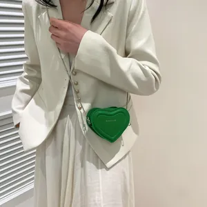 Détail macro d'un mini sac à bandoulière en forme de cœur vert vif avec une chaîne argent