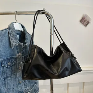 Detail of black slouchy tote bag with VVGNGGZHU embossed logo and knotted side straps