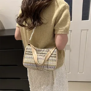 Close-up of bohemian woven straw bag with butterfly embroidery and pearl shoulder strap