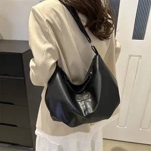 Detail of the high-quality black faux leather texture and metallic logo tag on this shoulder bag