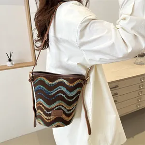 Women's knit bucket bag with zigzag pattern and brown leather strap in a home setting