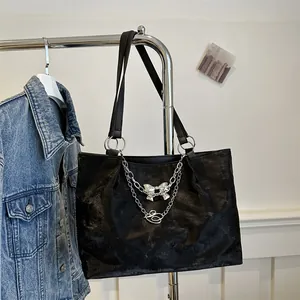 Detail of black tote bag featuring silver chain butterfly pendant and textured faux suede