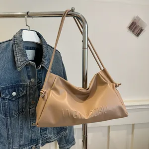 Detail of beige leather tote bag featuring 3D embossed lettering and soft knotted texture