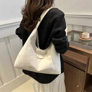 Detailansicht einer großen cremefarbenen Tote-Bag mit Markenlogo an einer Schulter