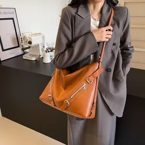 Caramel brown large capacity tote bag with silver zippers and buckles on a fashion model