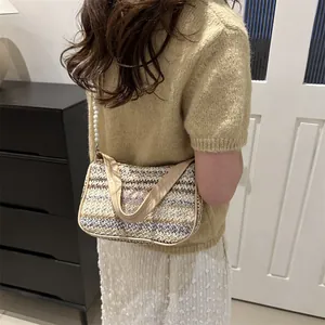 Detail of woven crescent bag featuring butterfly embroidery and pearl strap