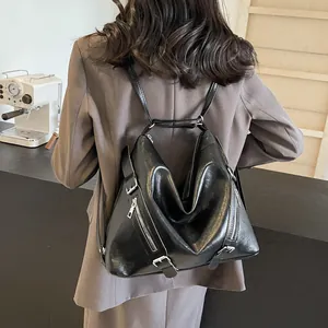 Detail of a black faux leather tote backpack with silver metallic zippers and buckles