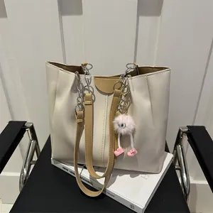 Detail of off-white tote bag with brown handles, silver chain, and Fashion embossing